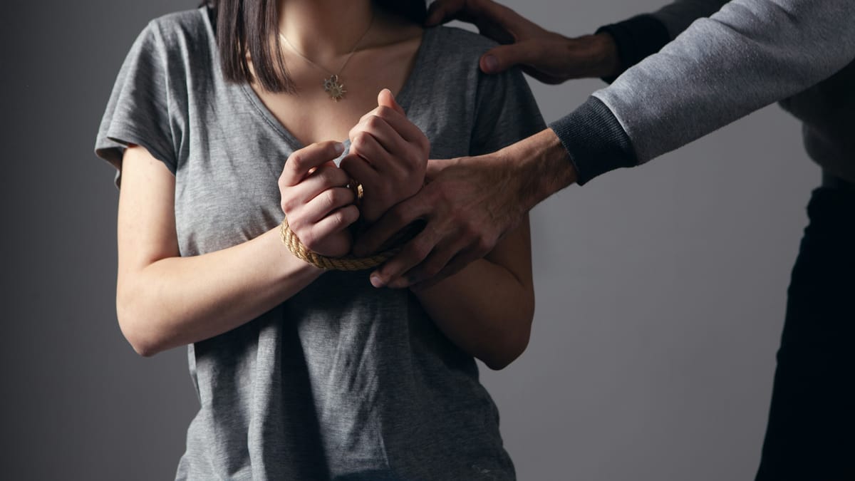 Une femme retenue par les poignets, évoquant l'emprise et le contrôle exercés dans une situation de harcèlement moral
